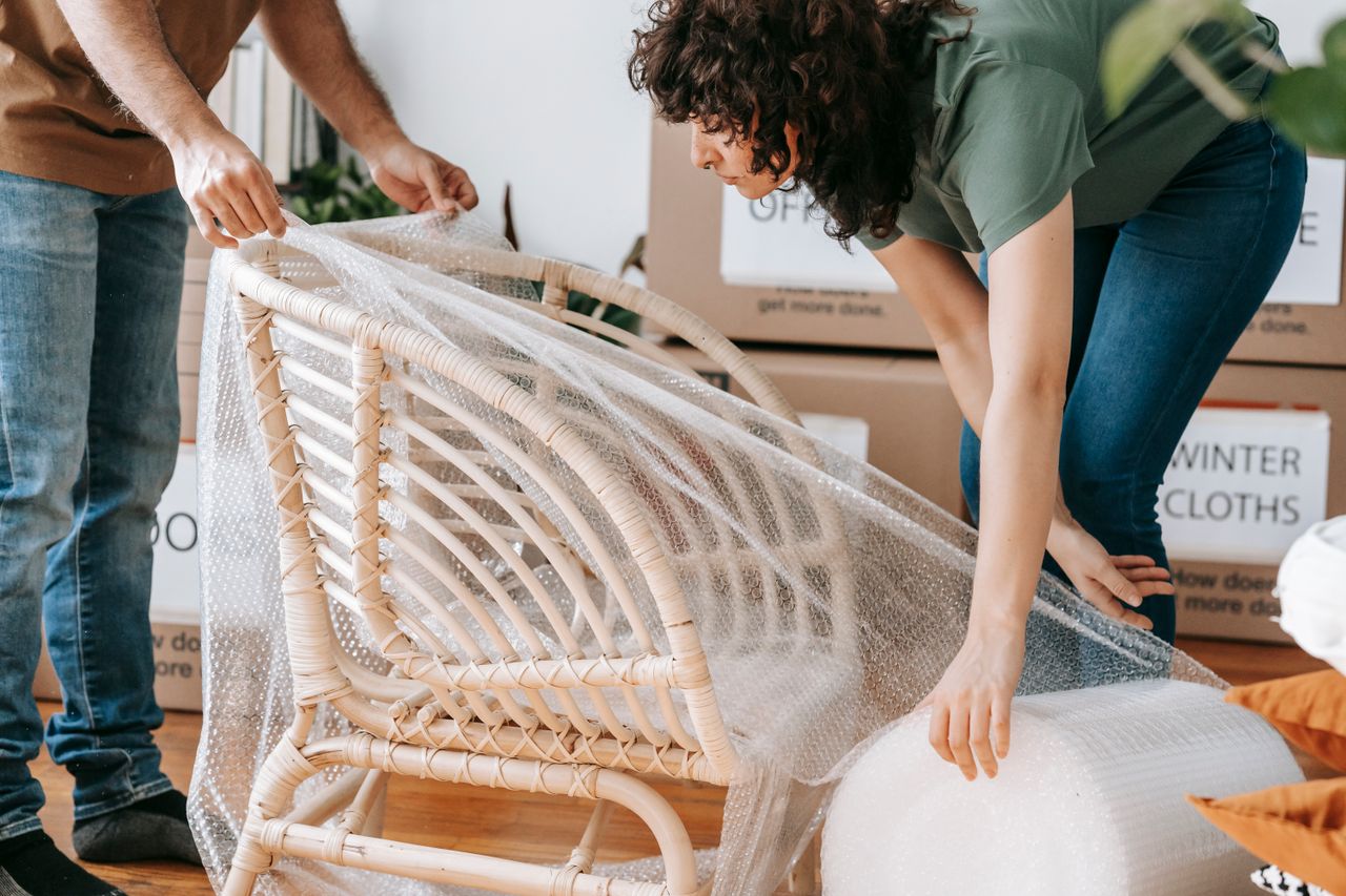 services-04 A couple uses bubble wrap to protect a chair while packing up their home for relocation.